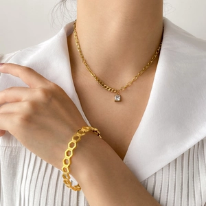 Detail of gold honeycomb cuff bracelet and square zircon pendant necklace on a model