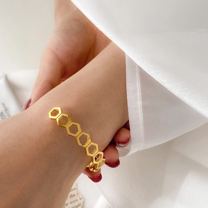 Detailed view of a gold honeycomb open cuff bracelet with hollow geometric hexagons