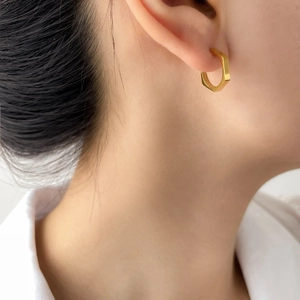 Modern minimalist golden hexagonal hoop earrings worn with a professional white shirt