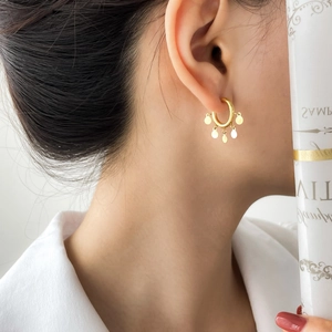 Close-up of golden hoop earrings with five small round sequin pendants on model
