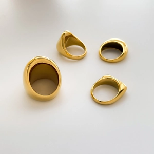 Dettaglio ravvicinato di quattro anelli d'oro spessi con forme geometriche lisce e concave