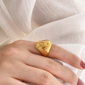 Dettaglio di un anello dorato spesso con finitura a specchio irregolare al dito