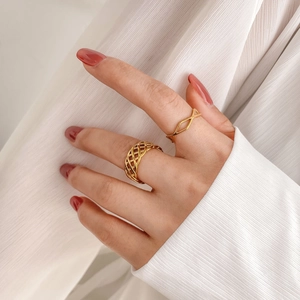 Detail of gold geometric hollow mesh and diamond lattice rings worn on hand