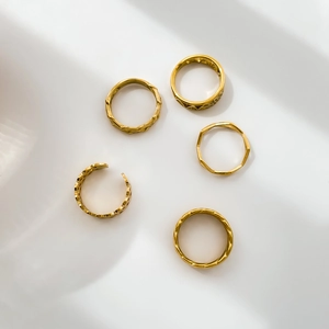 Detail of 5-piece gold-plated ring set featuring geometric patterns and woven textures