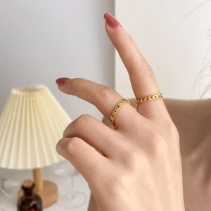 Gros plan de bagues dorées ajourées en étoile et chaîne sur les doigts en décor chic
