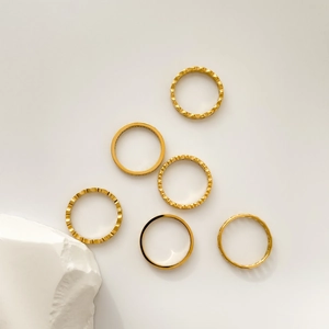 Gros plan d'un ensemble de six bagues dorées minimalistes aux textures géométriques