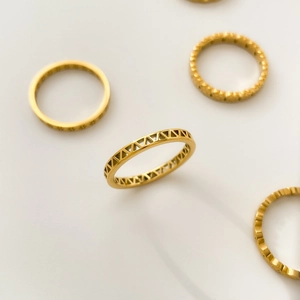 Détail d'une bague dorée minimaliste avec un design géométrique de triangle ajouré