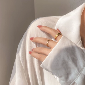 Close-up of golden heart pattern and delicate leaf rings worn on finger