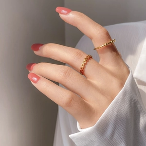 Detail of gold geometric hollow ring and minimalist beaded band on model hand