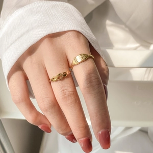 Detail of two gold geometric rings with vintage rectangle texture and hollow loop band