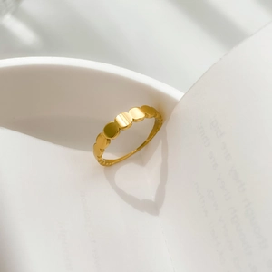 Detailed view of gold scalloped ring casting a romantic heart-shaped shadow on white background