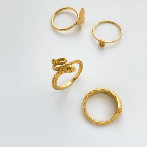 Macro view of four vintage gold rings including a snake design and butterfly charm
