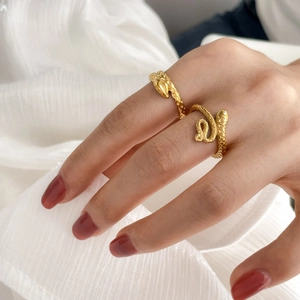 Close-up of gold snake rings with detailed scale texture on white fabric background