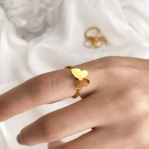 Detailed view of a golden butterfly ring with polished wings on a model's finger