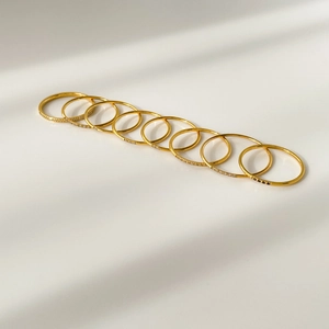 Top view of 10-piece gold stackable ring set with micro-pave zircons on white surface