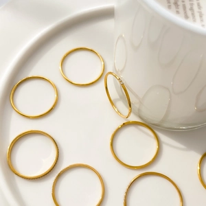 Macro detail of stacking gold rings with sparkling crystals on a white ceramic plate