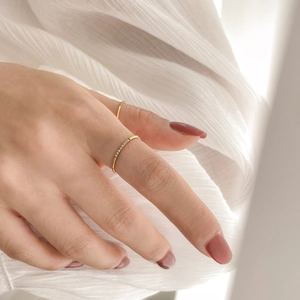 Detail of minimalist gold-plated rings with micro-pave crystals on a soft white fabric
