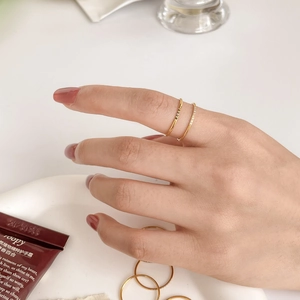 Detail of stacked thin gold rings with zircon stones on a soft lifestyle background