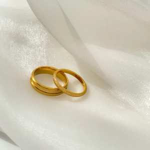 Détail de bagues de couple dorées avec finition mate brossée sur soie blanche