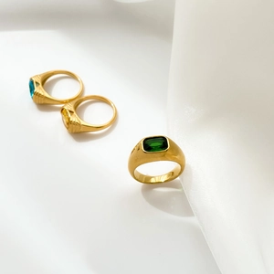 Three gold-plated rings with rectangular emerald, yellow and blue zircon stones on white silk