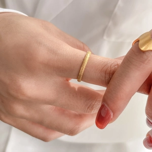 Vue détaillée d'une bague dorée mate avec finition poussière d'étoiles sur un doigt