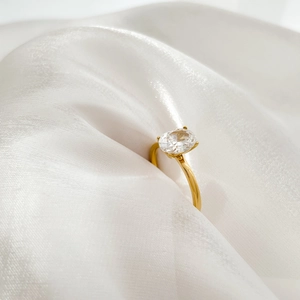 Detail of an oval clear zircon ring with a 18K gold-plated band on white silk background