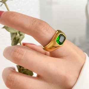 Close-up of a gold-plated titanium ring with a rectangular emerald zircon in a bezel setting