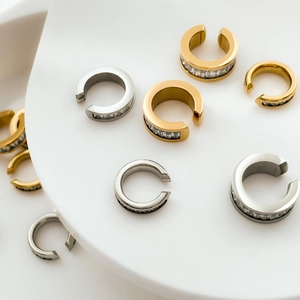 Dettaglio di orecchini a clip con zirconi placcati oro su vassoio in ceramica