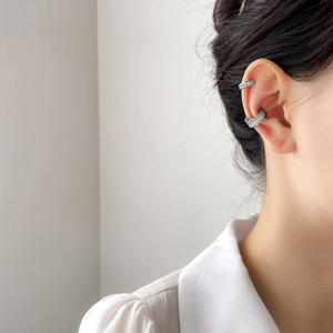 Dettaglio di ear cuff placcati in argento con zirconi scintillanti indossati sul modello