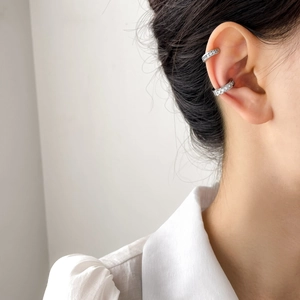 Dettaglio di ear cuff con zirconi brillanti indossati sulla cartilagine senza buco