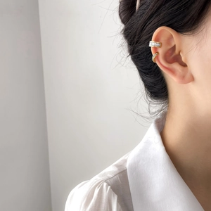 Dettaglio macro di ear cuff in titanio placcato oro con zirconi lucenti incastonati