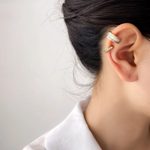 Dettaglio di un set di ear cuff dorati con zirconi rettangolari e tondi dal design elegante