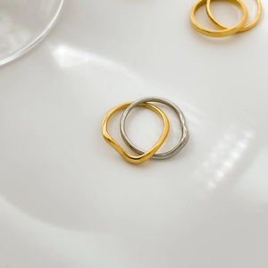Close-up of interlocking gold and silver wavy metal rings on a reflective white background