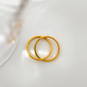 Close-up of minimalist interlocking double ring set with a polished gold finish and soft shadows