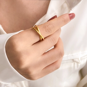 Detail of gold-plated minimalist interlocking crossover ring on female finger