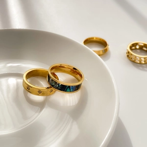 Ensemble de bagues dorées avec nacre d'abalone et motifs d'étoiles sur céramique blanche