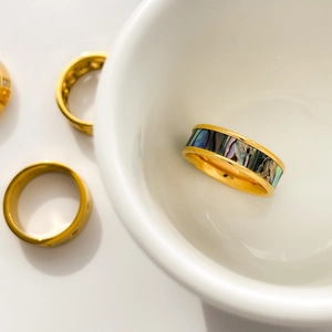Détail d'une bague large dorée avec nacre d'abalone et ensemble d'anneaux