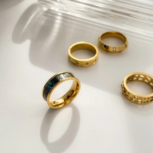 Vue détaillée de bagues dorées avec nacre et bijoux étoile sur fond blanc épuré