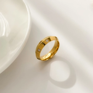 Gros plan d'une bague géométrique dorée avec zircon carré et facettes polies