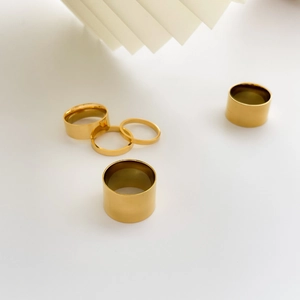 Minimalist stackable gold-plated stainless steel rings in varied widths on white background