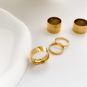Detailed view of five-piece minimalist gold rings set on clean white background