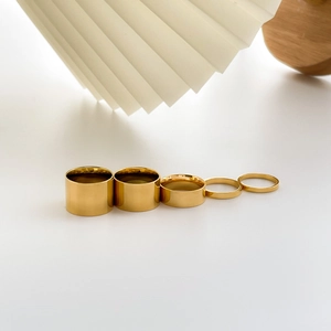 Set of five minimalist polished gold rings with varying widths on a clean white surface