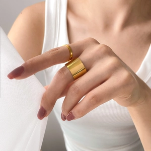 Close-up of wide and thin gold rings set with a high-polished finish on finger