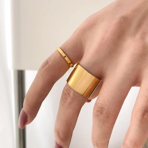 Close-up of minimalist gold plated wide cigar band and thin ring set on woman finger