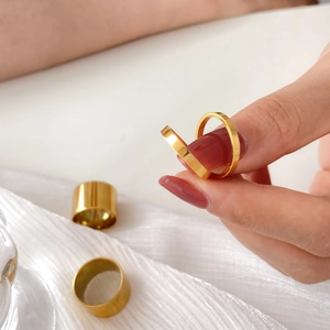 Detailed view of four polished gold rings in various widths on white silk fabric