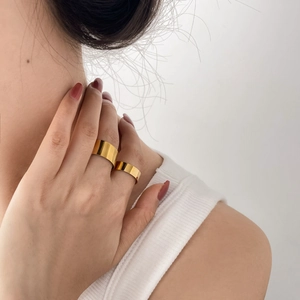 Minimalist wide gold rings set on female hand with polished finish for stacking style