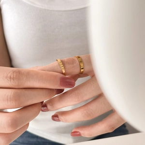 Close-up of polished gold wide band rings worn on index and middle fingers
