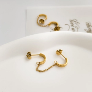 Macro detail of gold U-shaped double stud earrings with connecting chain link