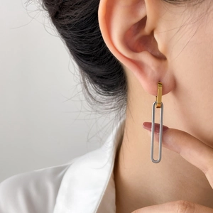 Detailed view of two-tone geometric U-shaped earrings on model in minimalist style
