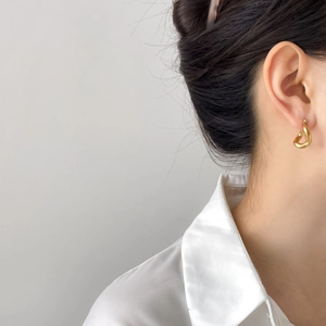 Elegant gold U-shaped geometric drop earrings worn by a model in a minimalist style